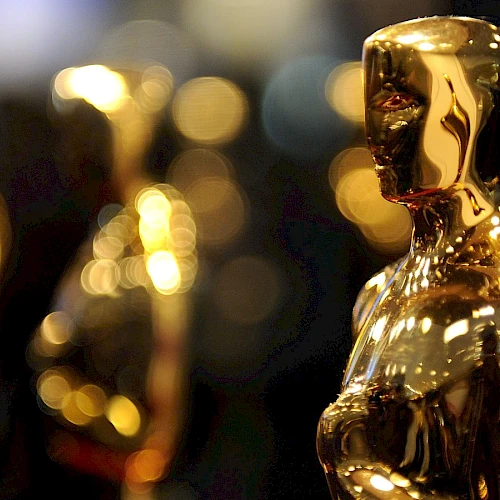 The image shows several golden Oscar statuettes, which are awarded as trophies for excellence in the film industry.