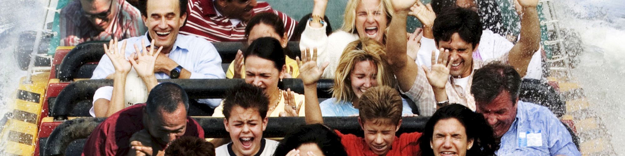 A group of people riding a water-based amusement park attraction, with the front of the boat labeled 