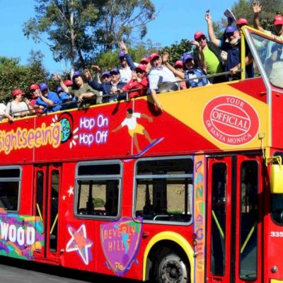 A red double-decker bus filled with people on a sightseeing tour, labeled with 