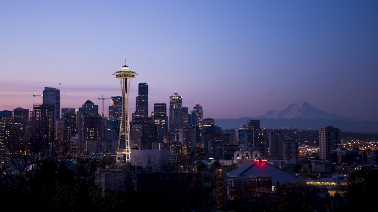 This image features the Seattle skyline at dusk, showcasing the Space Needle prominently, with Mount Rainier visible in the background.