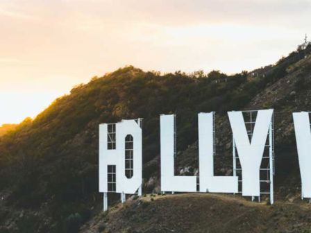 An iconic white sign on a hillside under a partly cloudy sky during sunset, with only partial letters visible.